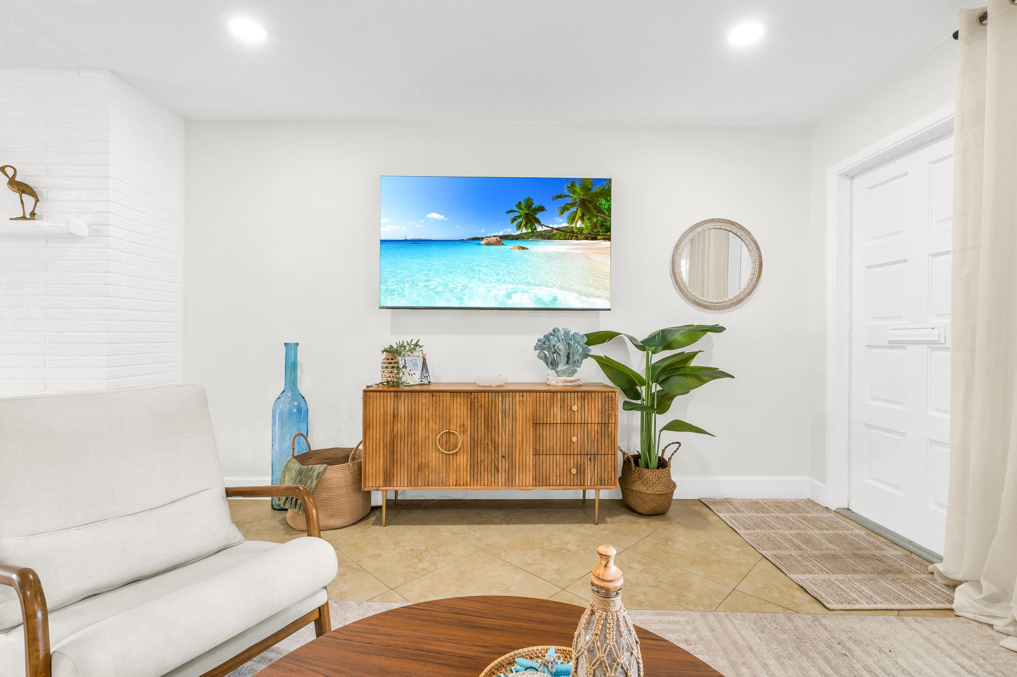 Bright and coastal-inspired, the living room features a plush sofa, stylish accent seating, a large Smart TV, and soothing ocean-toned décor—perfect for relaxing after a day at the beach.