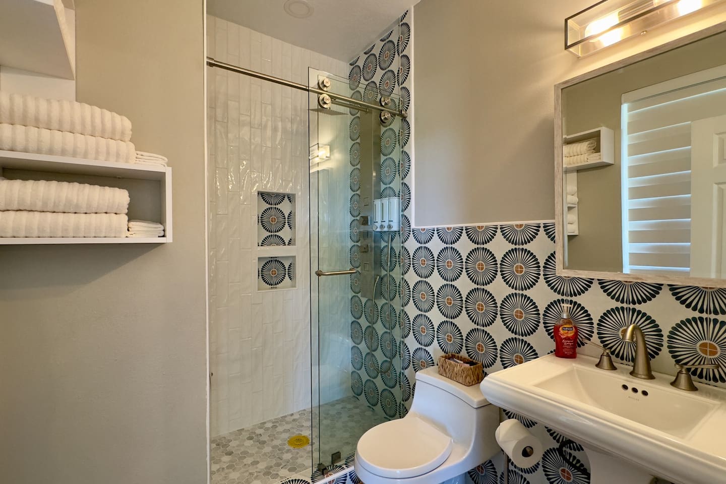 A pedestal sink with brushed nickel fixtures, wall-mounted towel storage, and a clean white toilet ensure convenience