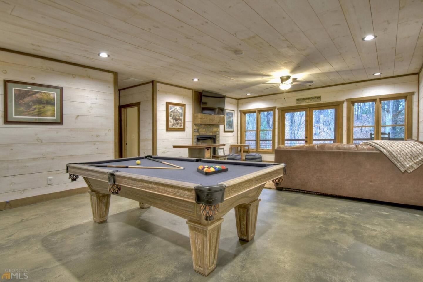 Game room on lower level with pool table and lounge space.  French doors lead to balcony with hot tub and rocking chairs.  Gas fireplace