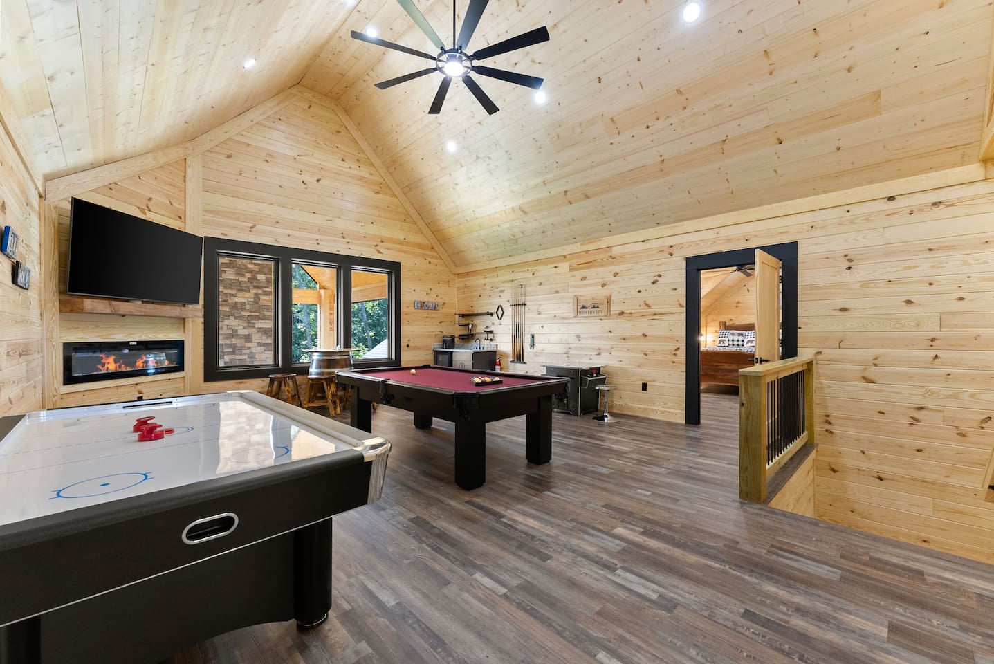 Challenge your friends to a game of pool or air hockey in this spacious loft-style game room, complete with a mounted TV and electric fireplace for cozy fun.