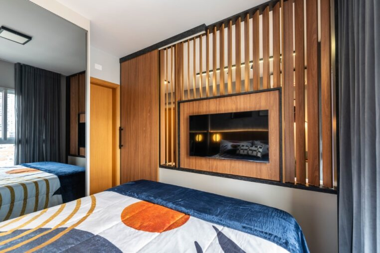 Detalhe da TV giratória entre quarto e sala Design inteligente com divisória de madeira que garante privacidade e funcionalidade ao ambiente.