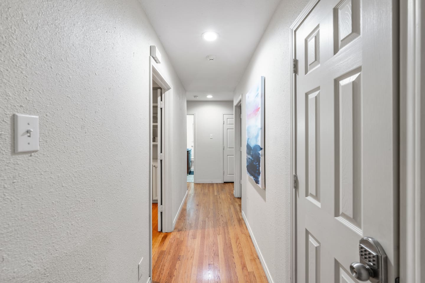 Bright, inviting hallway with sleek flooring and soft lighting connecting bedrooms and living areas.