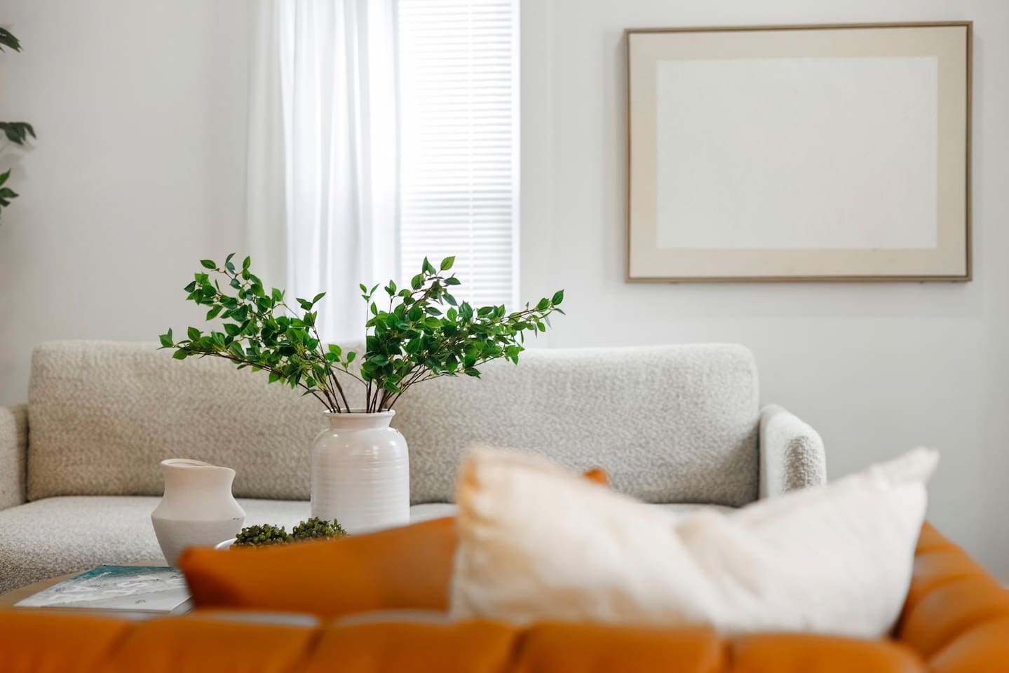 Bright, cozy living room with coastal tones, plush seating, and a calm, airy feel. Living room has two couches, one plush queen sofa bed and one leather couch.