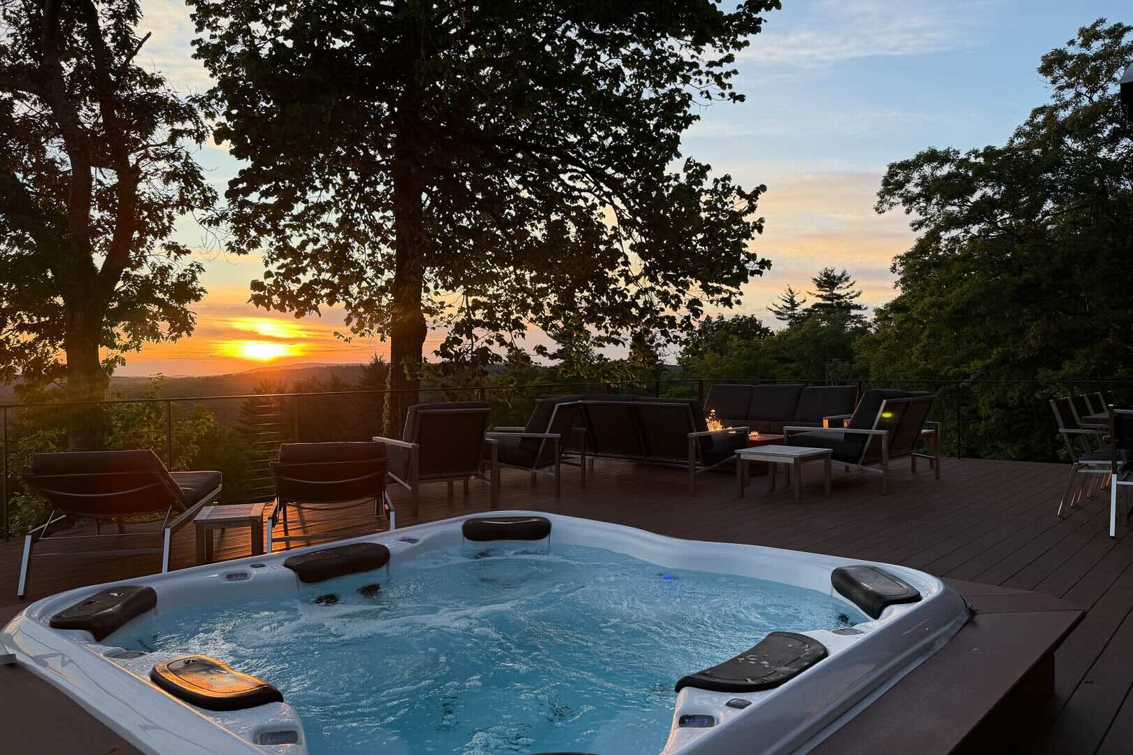 Hot tub and fire table at night on the deck at Sunset Falls &mdash; the Berkshires ridgeline beyond