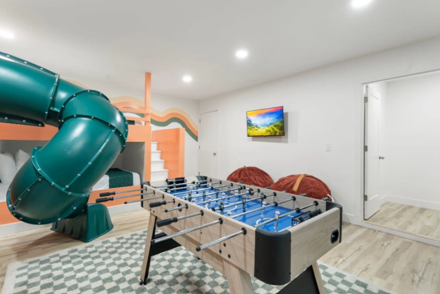 Another angle of the game room shows just how much is packed in here, from the slide to a mounted TV for background entertainment during game time.
