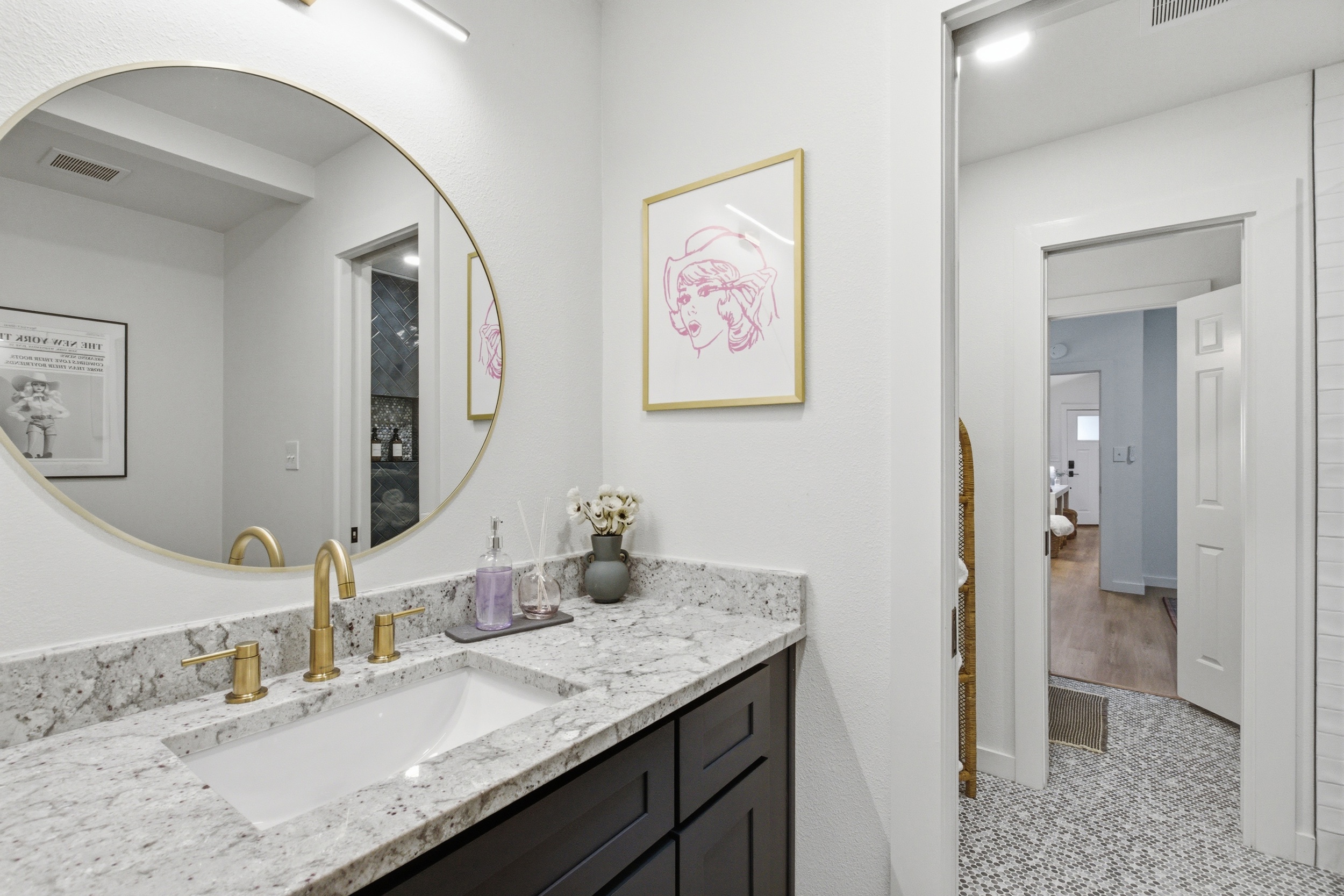 Marble vanity with gold hardware and round mirror. Hairdryer provided. Stocked with all bath essentials by Ginger Lily Farms. Shared bathroom serving Bedrooms 3 and 4, Arlington TX.