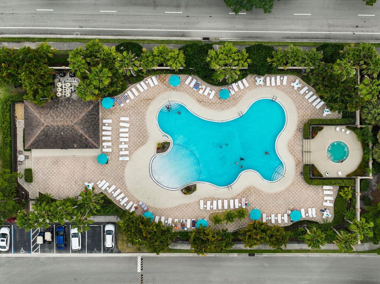Aerial view of the resort-style community pool and spa with lounge seating and tropical surroundings.