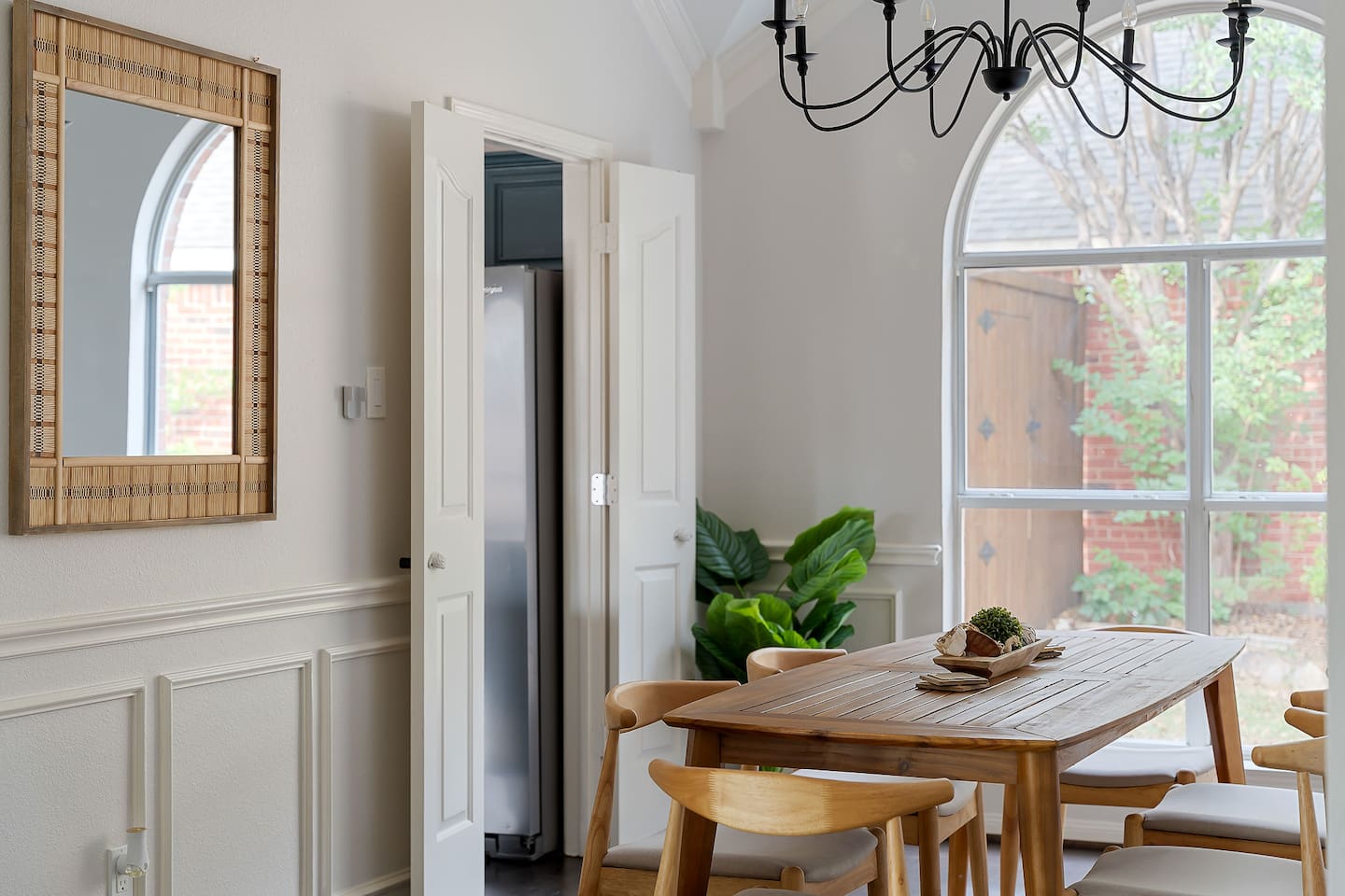 Enjoy a cozy dining area adorned with a wall mirror, inviting in the outdoor scenery through a window at the back.