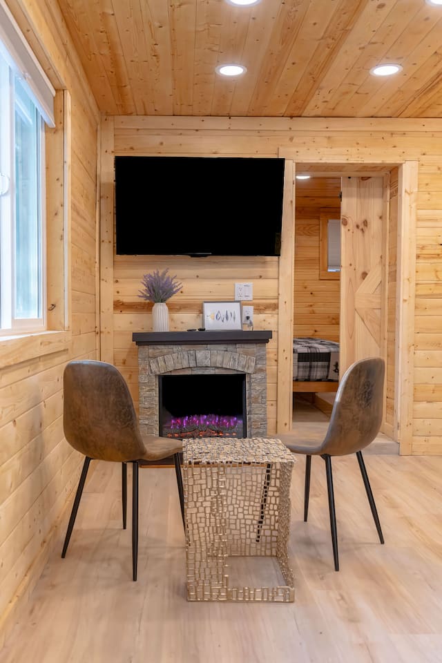 Sunlight fills this cozy corner, highlighting juniper pines and the firepit. With a warm fireplace, a big 55-inch TV, and chic seating, it’s the perfect spot to kick back, sip your coffee, and debate whether to explore or just lounge all day!