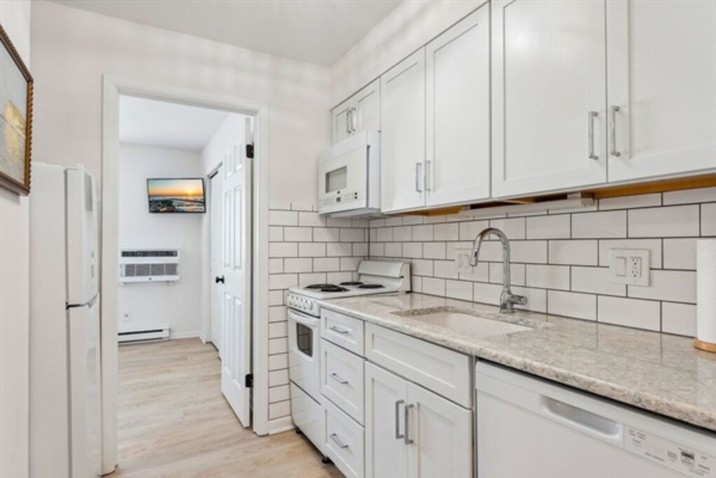 Bright kitchen featuring white cabinetry and essential appliances.