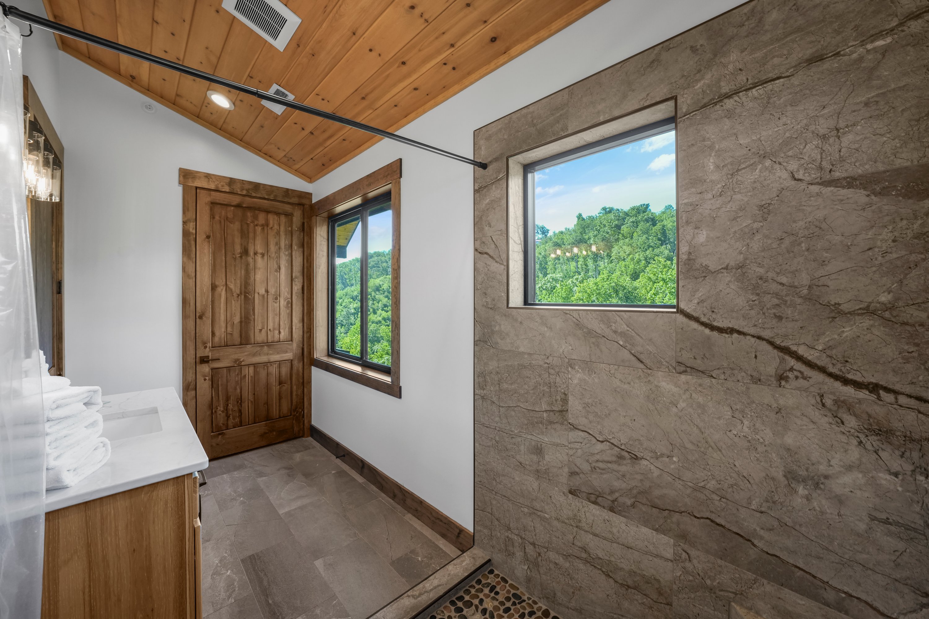 King Suite with vaulted ceilings an x-large TV. Unwind in the en-suite bathroom featuring a luxurious walk-in shower with a natural river rock floor, bringing  the Smoky Mountains indoors for a spa retreat.