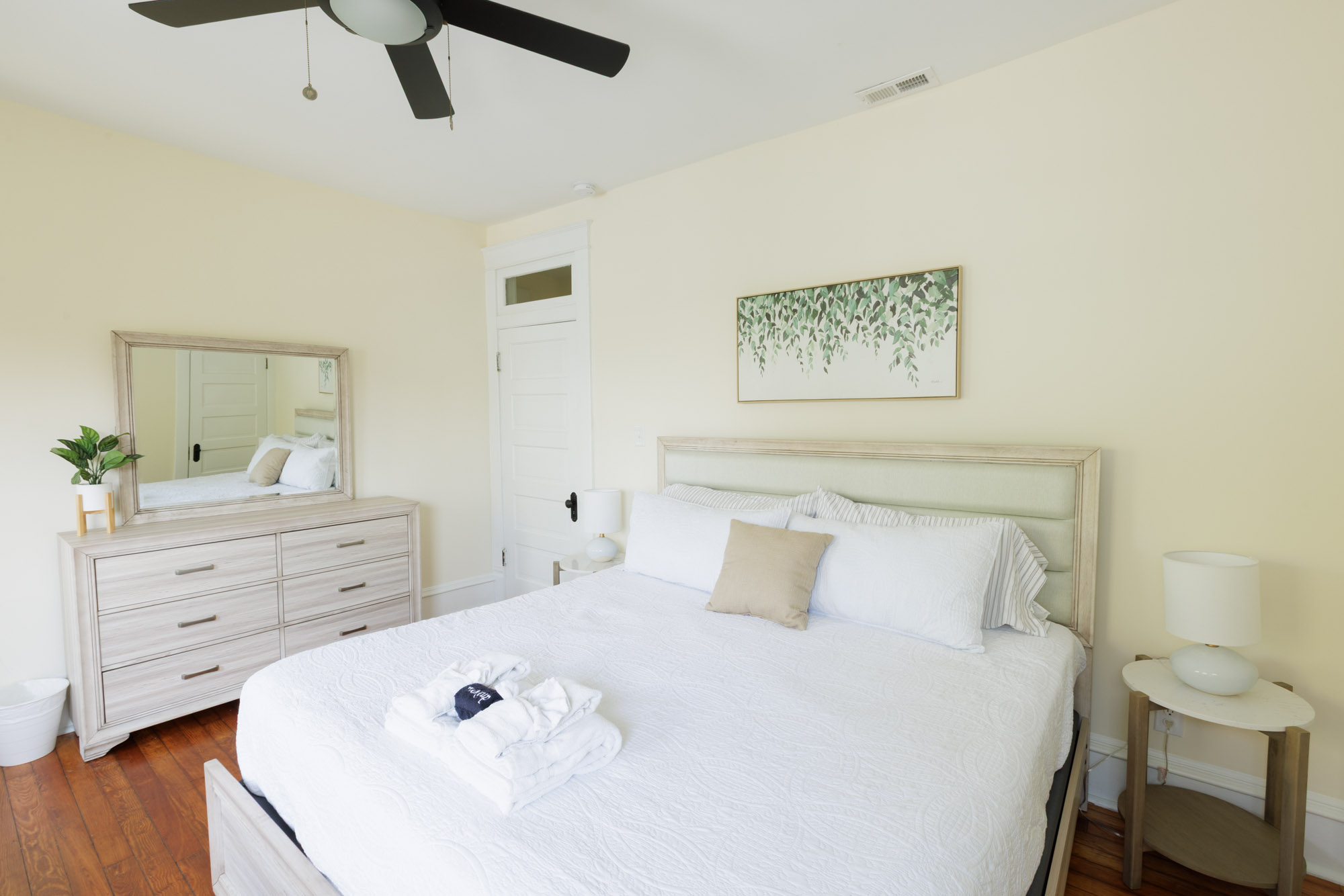 Large king Bedroom with large dresser and love seat and large bay windows.