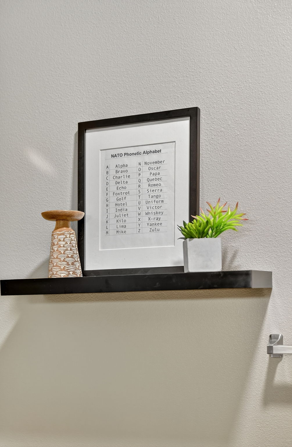 Unique wall shelf with framed décor and greenery. Small touches like this add charm and character to the modern design.