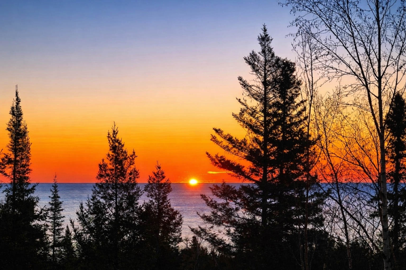 Wake up slowly at Treetops and step out onto the deck with a warm cup of coffee in your hand as the sun begins to rise over Lake Superior. The first light peeks through the trees, glowing softly between the branches before spilling out across the water.