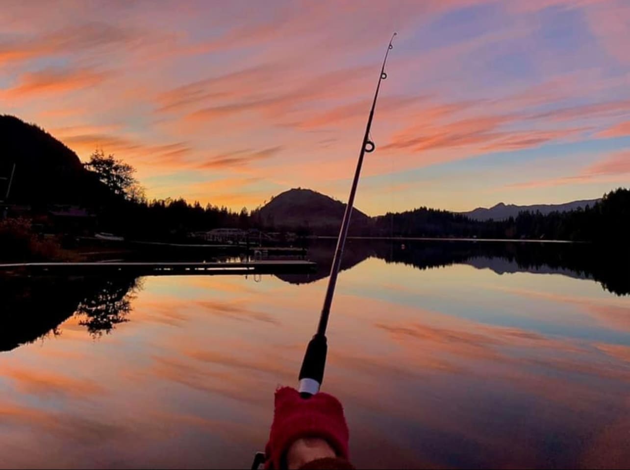 Fishing pole in hand with the lake glowing at sunset.