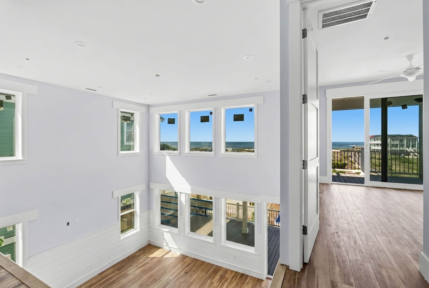 The ultimate gathering space. This expansive two-story living room offers ocean views, ample seating, an 85" smart TV, and an open floor plan that flows seamlessly into the kitchen and dining area. (Photo taken during construction.)