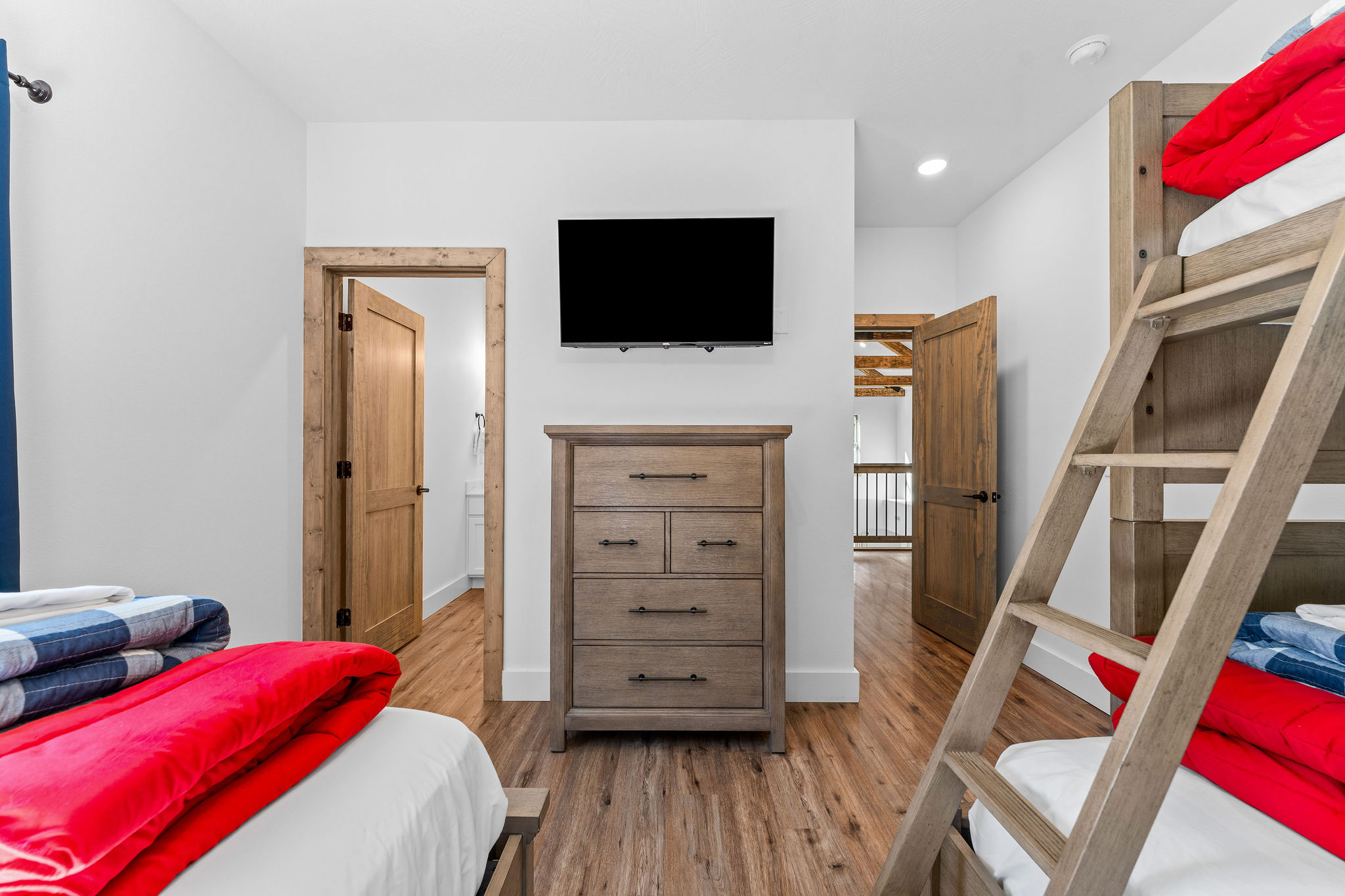Spacious sleeping area featuring bunk beds, a dresser, and TV for added comfort and convenience. Every bedroom has its own attached ensuite bathroom.