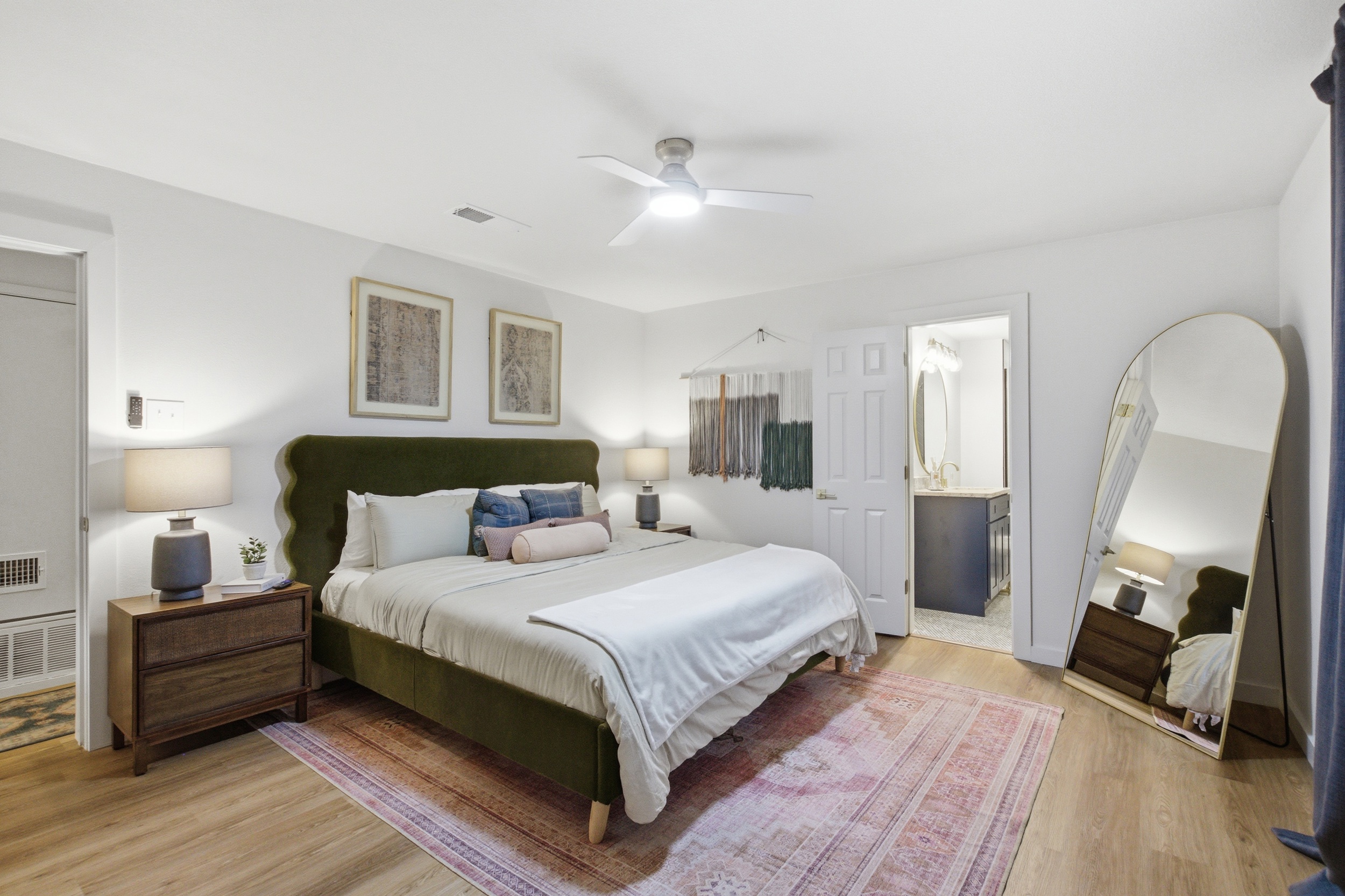 King Bed with full-length mirror, warm lighting, and room-darkening shades. Clothing storage and hardwood floors throughout. One of two King suites in this group rental.