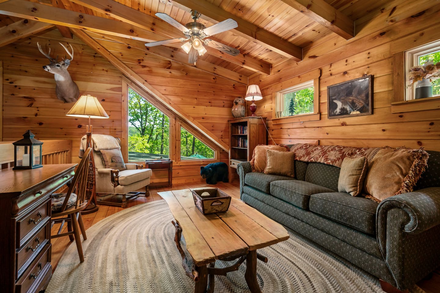 Cozy loft retreat with warm wood finishes, comfortable seating, and peaceful woodland views