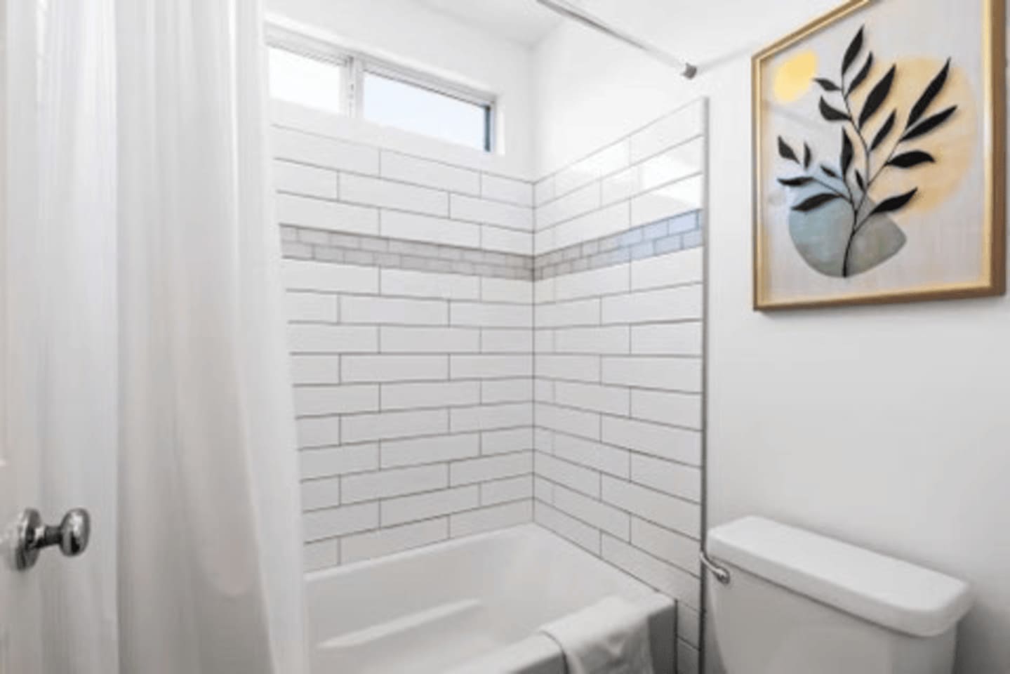 Clean, modern bathroom with a bathtub and shower, stocked with shampoo, shower gel, body soap, and essentials for a comfortable stay.