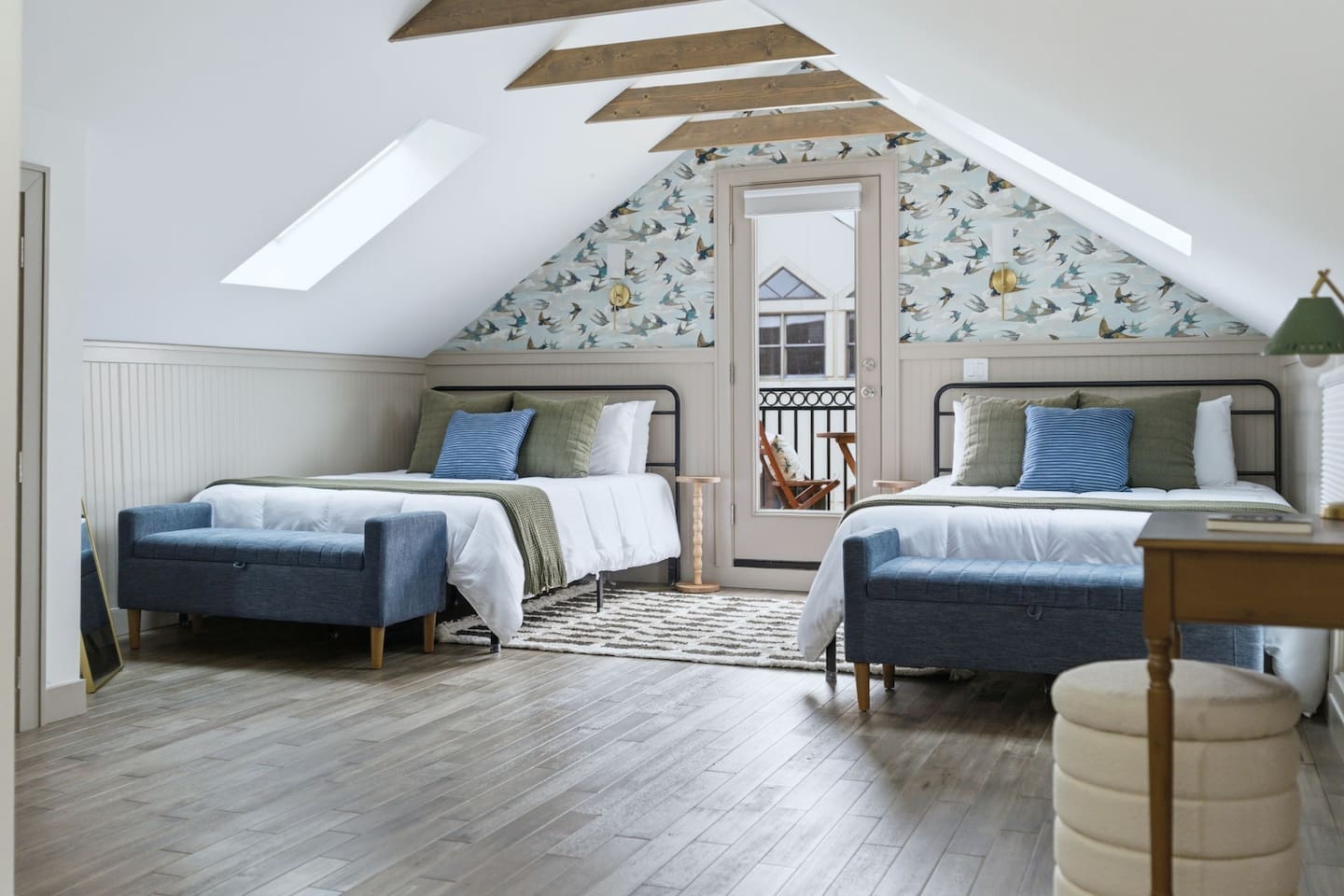 Another view of the loft bedroom showcasing two plush beds, natural light from skylights, and direct access to a private balcony.