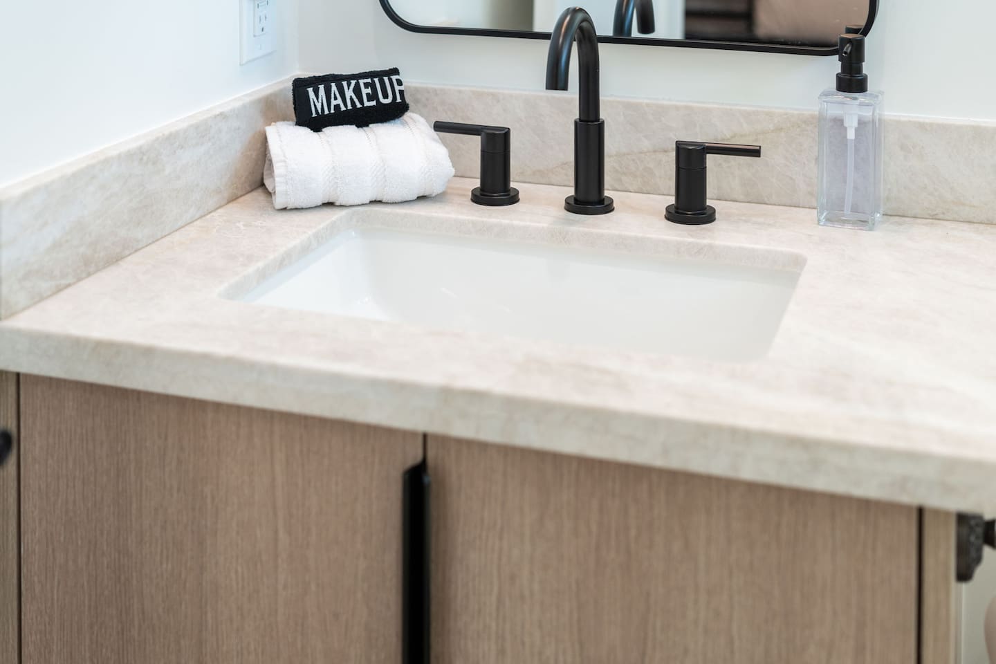 Clean and stylish vanity with quartz countertop, black matte fixtures, and fresh towels for your stay.