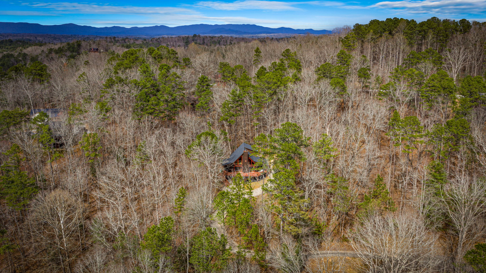 This breathtaking drone-captured view from above highlights the property’s stunning surroundings, including lush trees and scenic mountain landscapes.