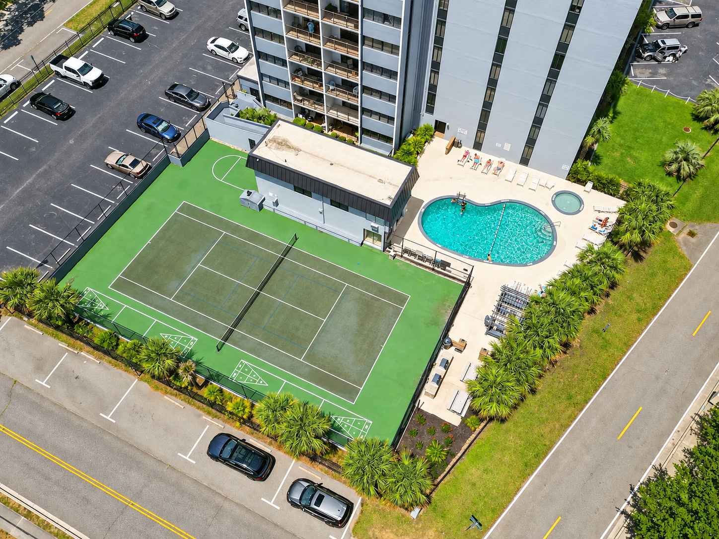 Aerial view of Holiday Towers with the shared pool, hot tub, tennis court, and guest parking all in one easy-access area.