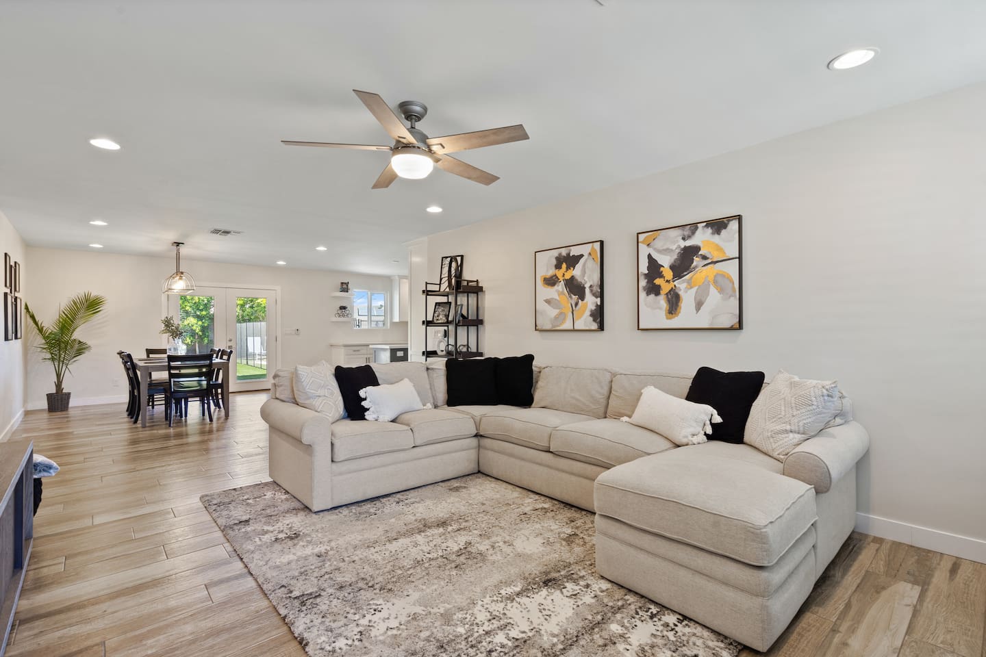 Open living room with large sectional seating, ceiling fan, and easy flow into the dining area and kitchen.