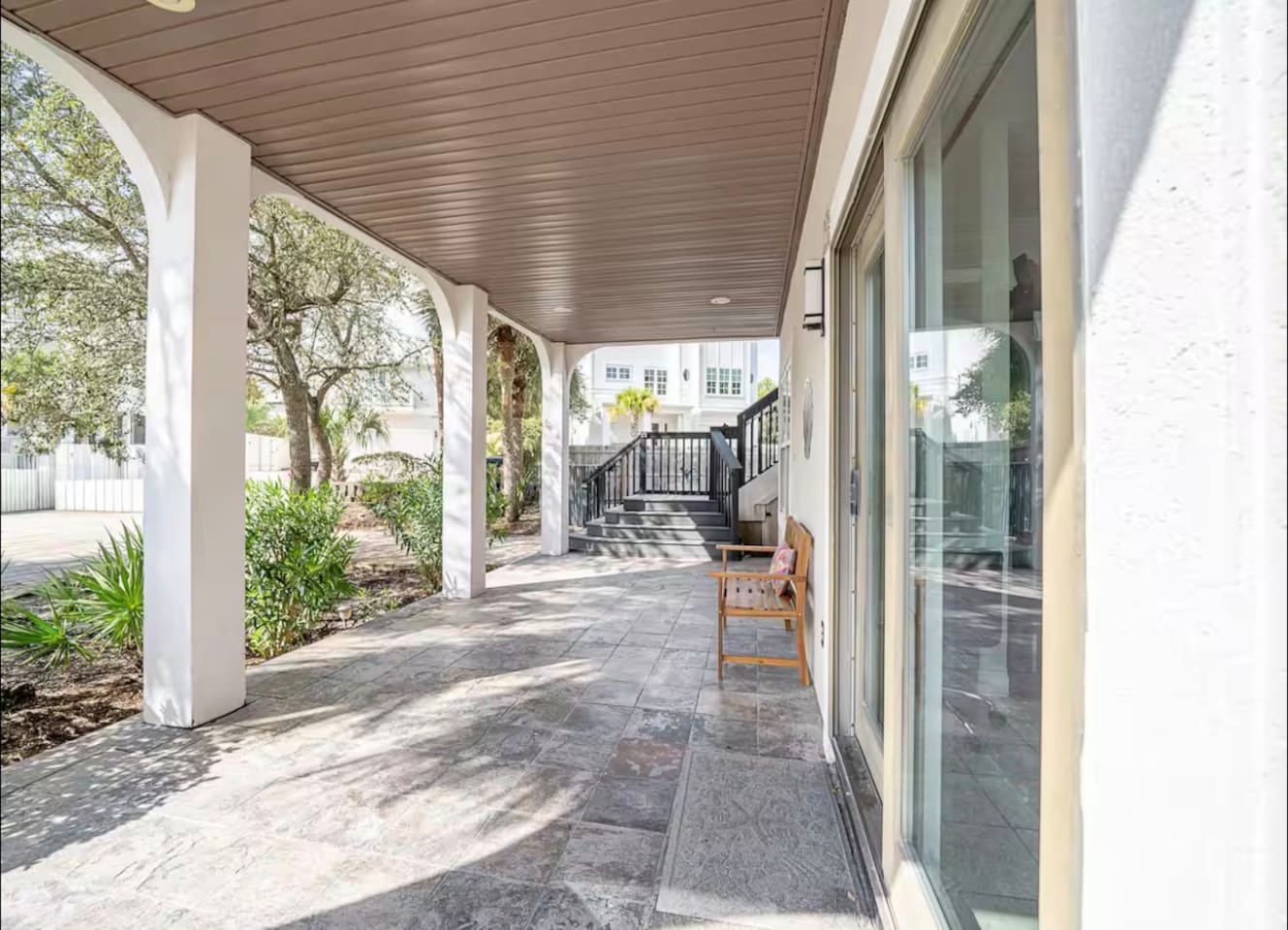 Covered ground-level patio and shaded walkway offering seamless indoor-outdoor access through large sliding glass doorS
