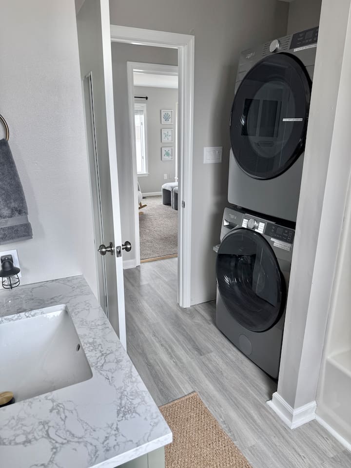 The laundry area features a modern, stacked washer and dryer unit.