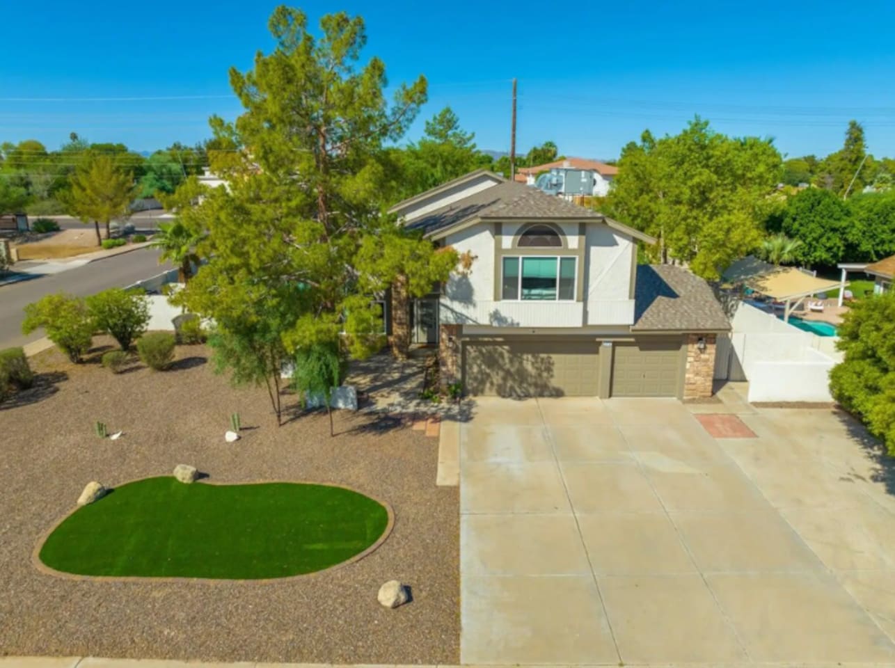 Two-story home with putting green, mature trees, spacious driveway, and resort-style backyard.