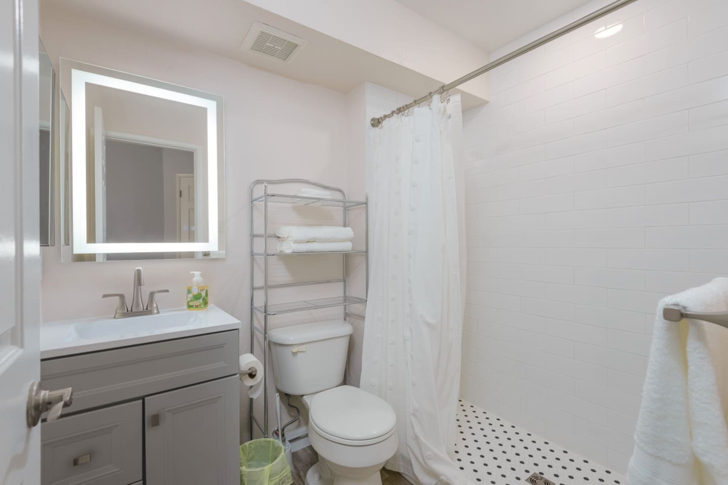 Full bathroom with a shower, vanity storage, fresh towels, and simple essentials for daily use.
