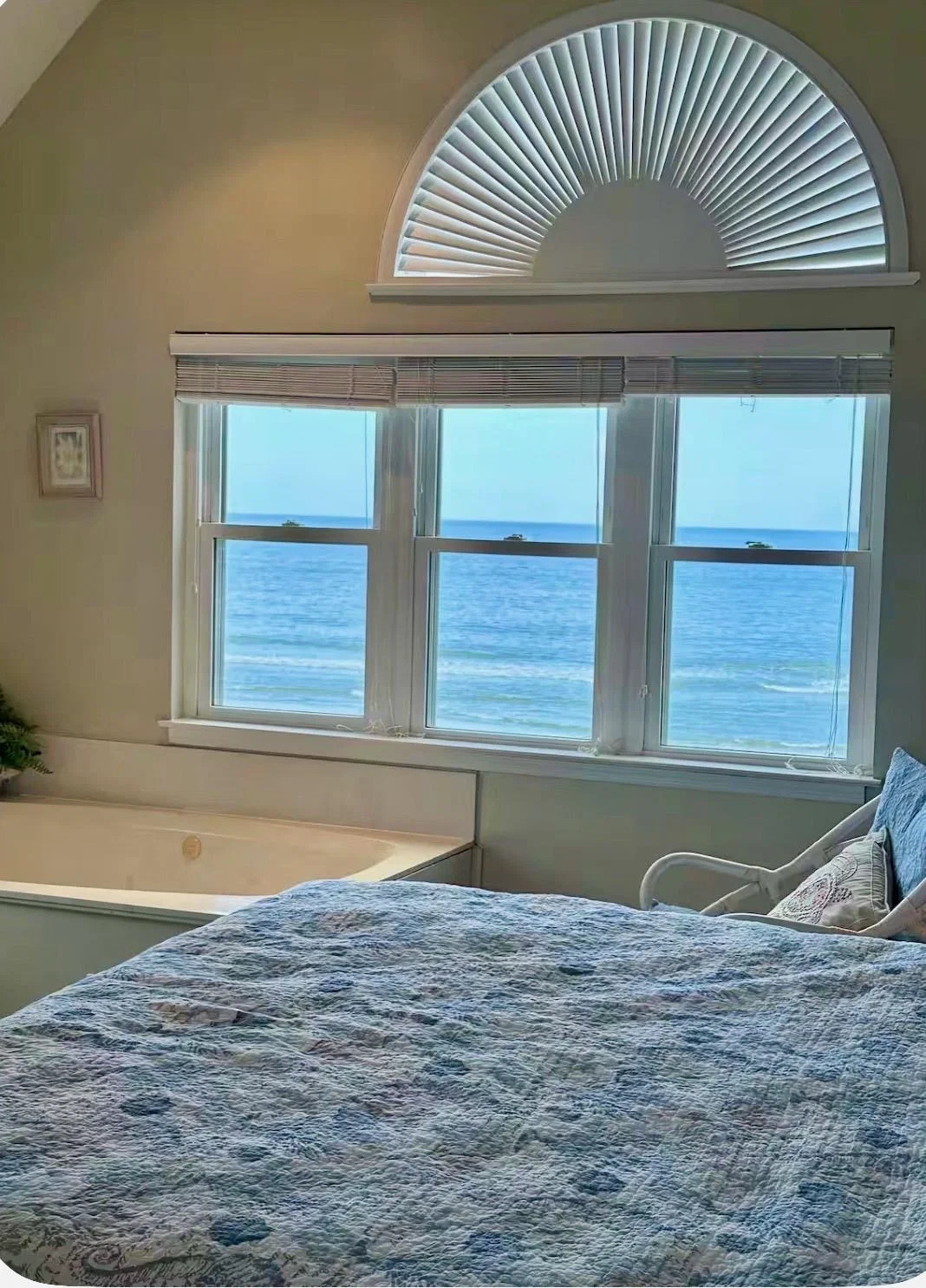 Primary bedroom: king bed with jetted tub beneath ocean-view windows