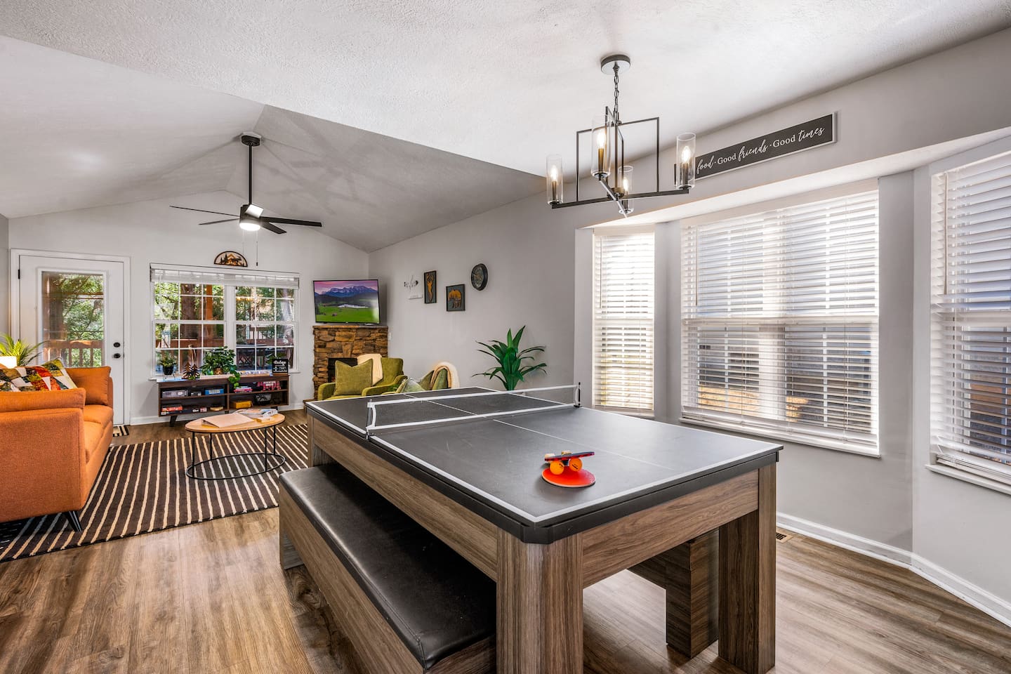 Bright and inviting game room with a convertible pool and ping pong table, cozy seating, and large windows for natural light