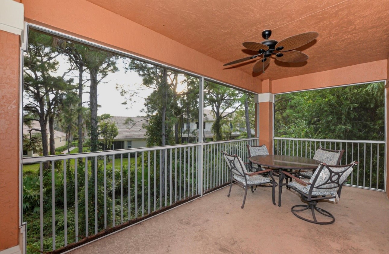 Spacious screened balcony with seating and peaceful views of the surrounding greenery.