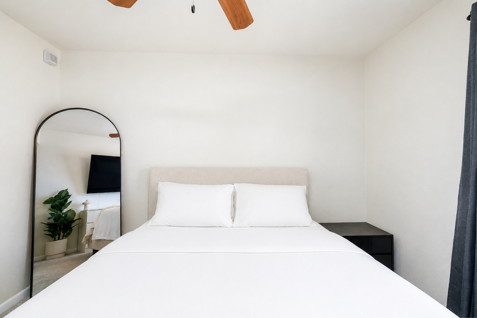Bedroom with a queen bed, dresser, ceiling fan, and natural light for a comfortable rest.
