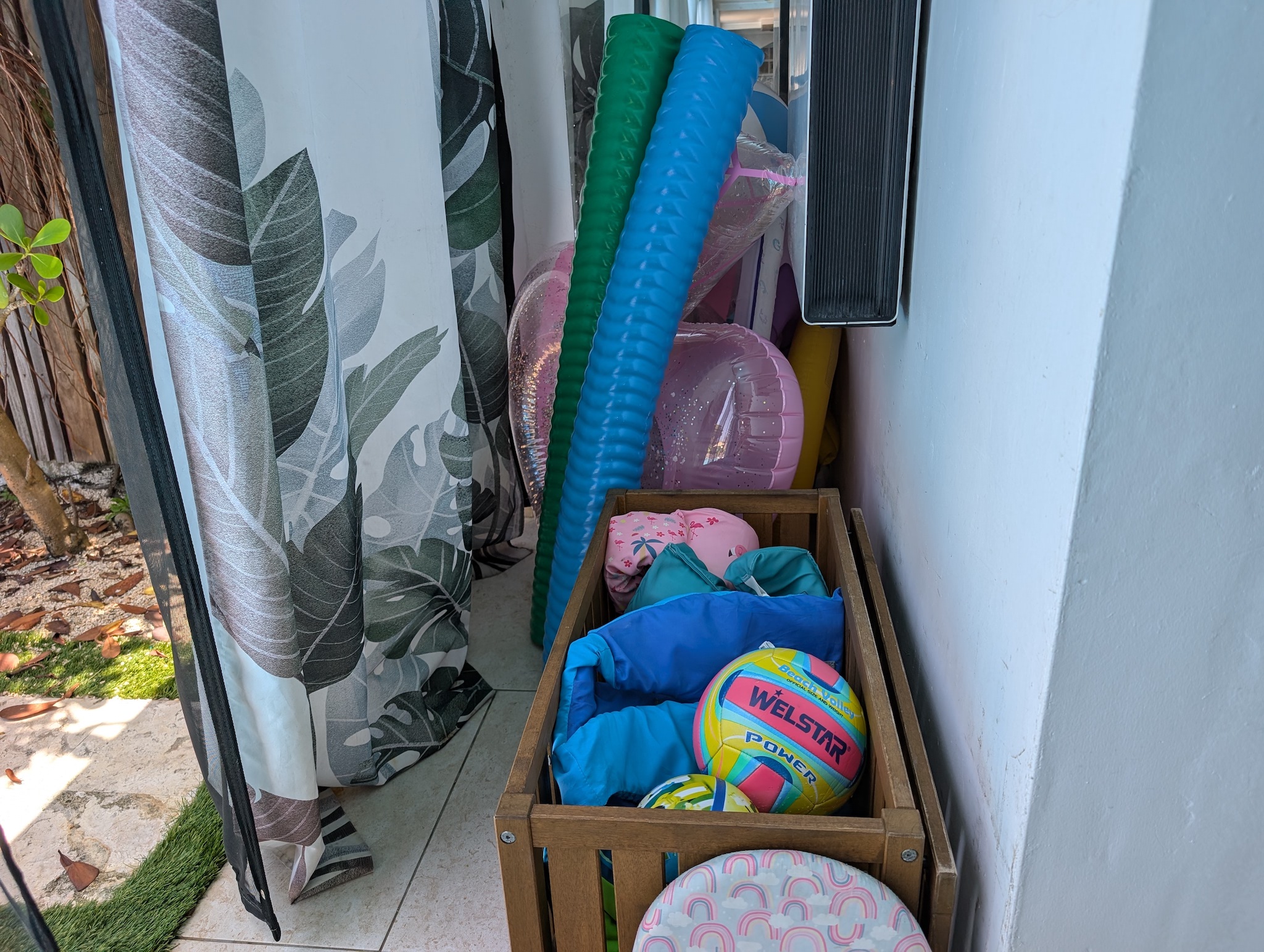 Wooden storage bin at Villa Coral packed with complimentary beach volleyballs, pool toys, life jackets, puddle jumpers, and colorful pool noodles in Dorado, Puerto Rico.