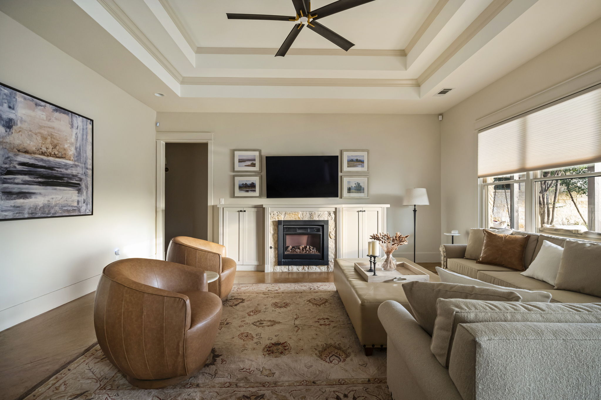 A spacious and inviting area featuring a large L-shaped sofa, two bucket chairs, and a TV for entertainment.
