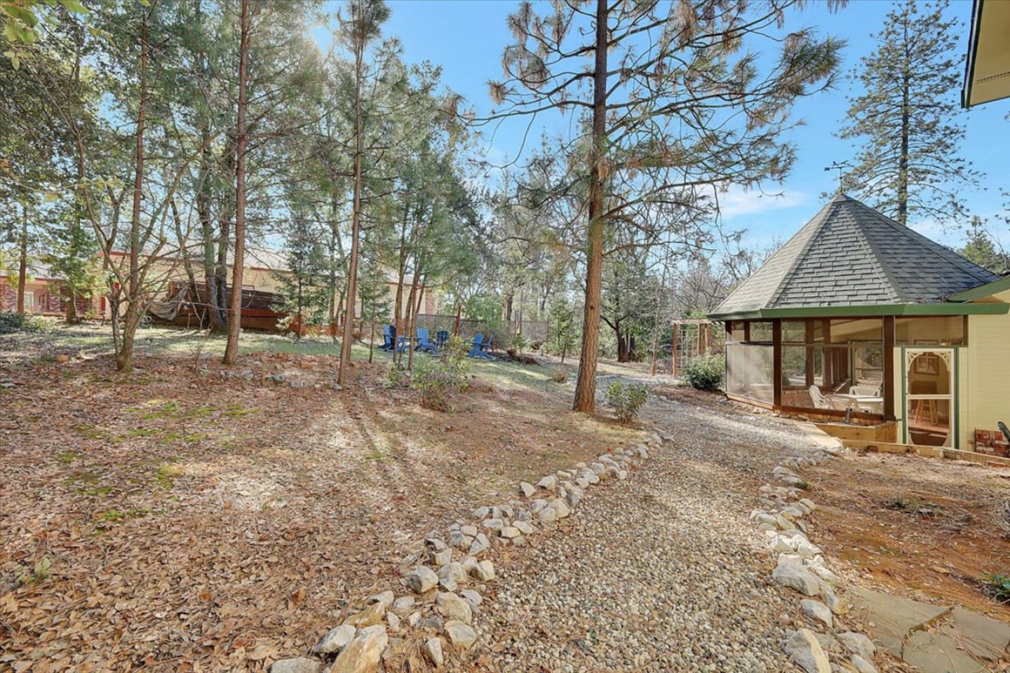 Wooded outdoor space with a gravel path, fire pit seating, and room to enjoy the trees.
