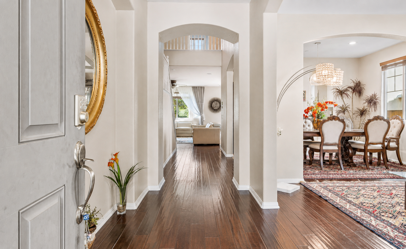 Entry hallway with polished wood floors, arched openings, and easy access to the dining and sitting rooms.