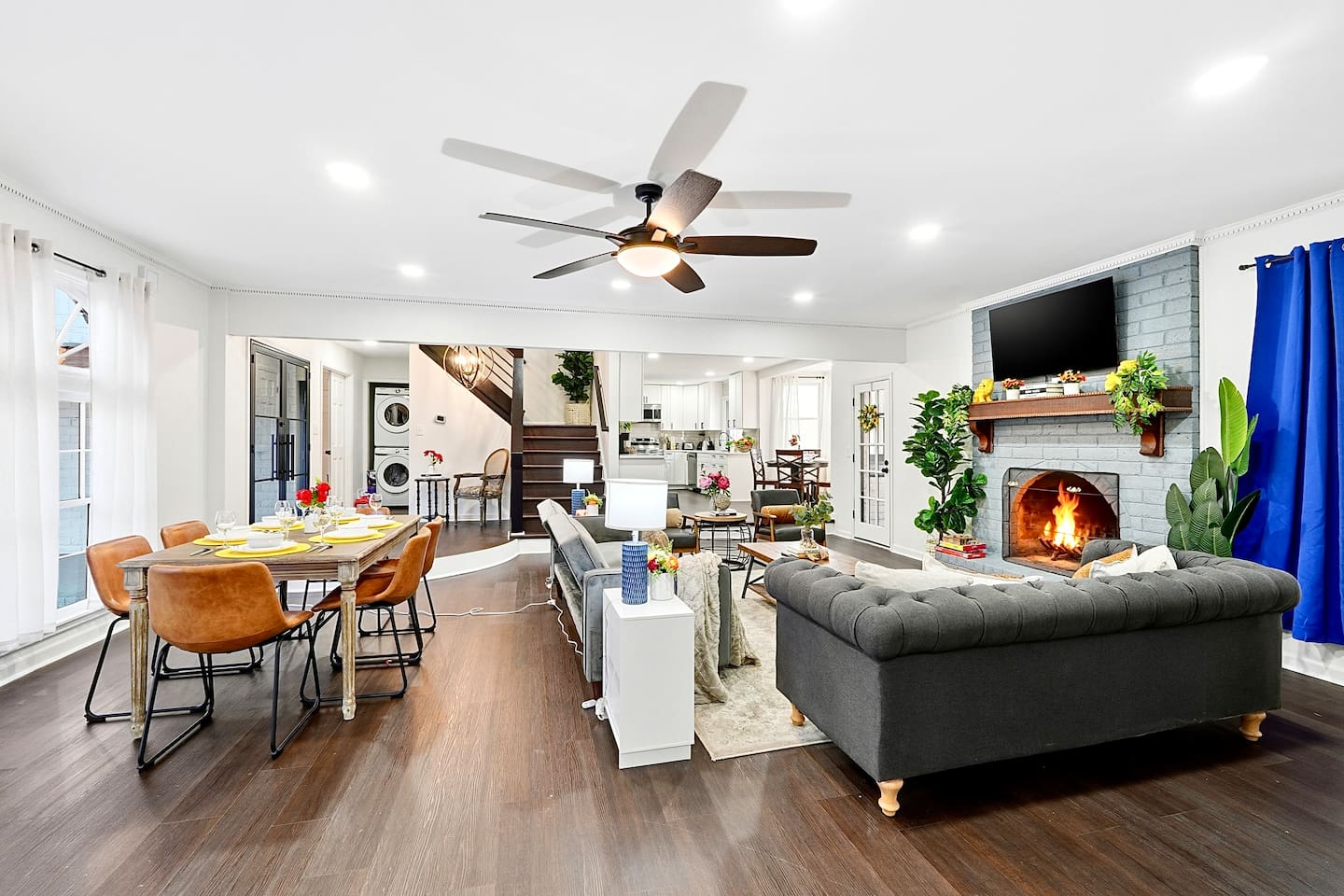 Warm and welcoming living room with two comfortable couches, two chairs, indoor plants, a cozy fireplace, and a TV powered by Google TV. Conveniently located as you walk through the front door and straight ahead from the primary side entrance. 