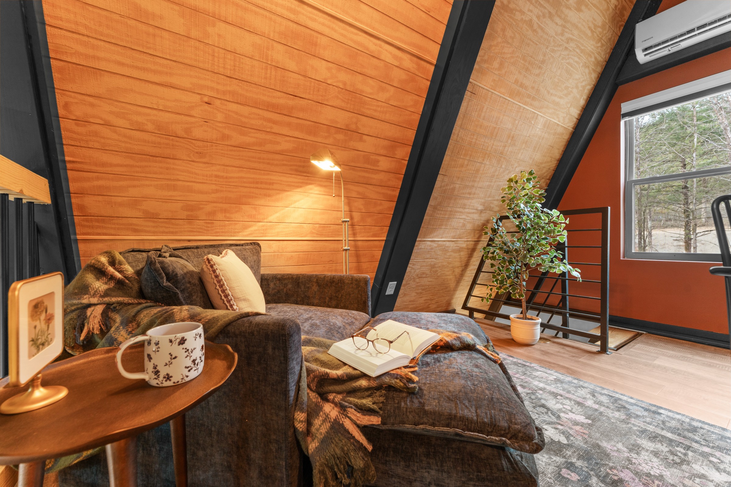 Loft reading nook with a sofa chair and window to the woods. Grab a book, a throw and a mug, and settle in for a quiet afternoon.