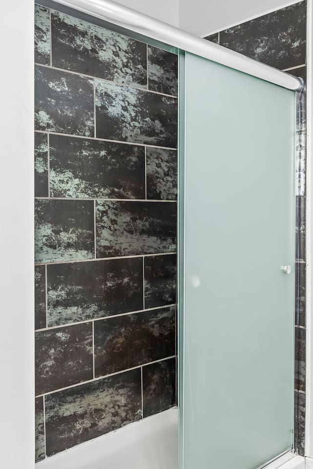 Walk-in shower with frosted glass door, stylish tile surround, and modern fixtures.