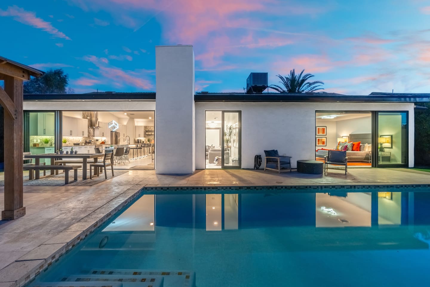Enjoy seamless indoor-outdoor living as the kitchen, dining, and pool spaces glow under the evening sky.