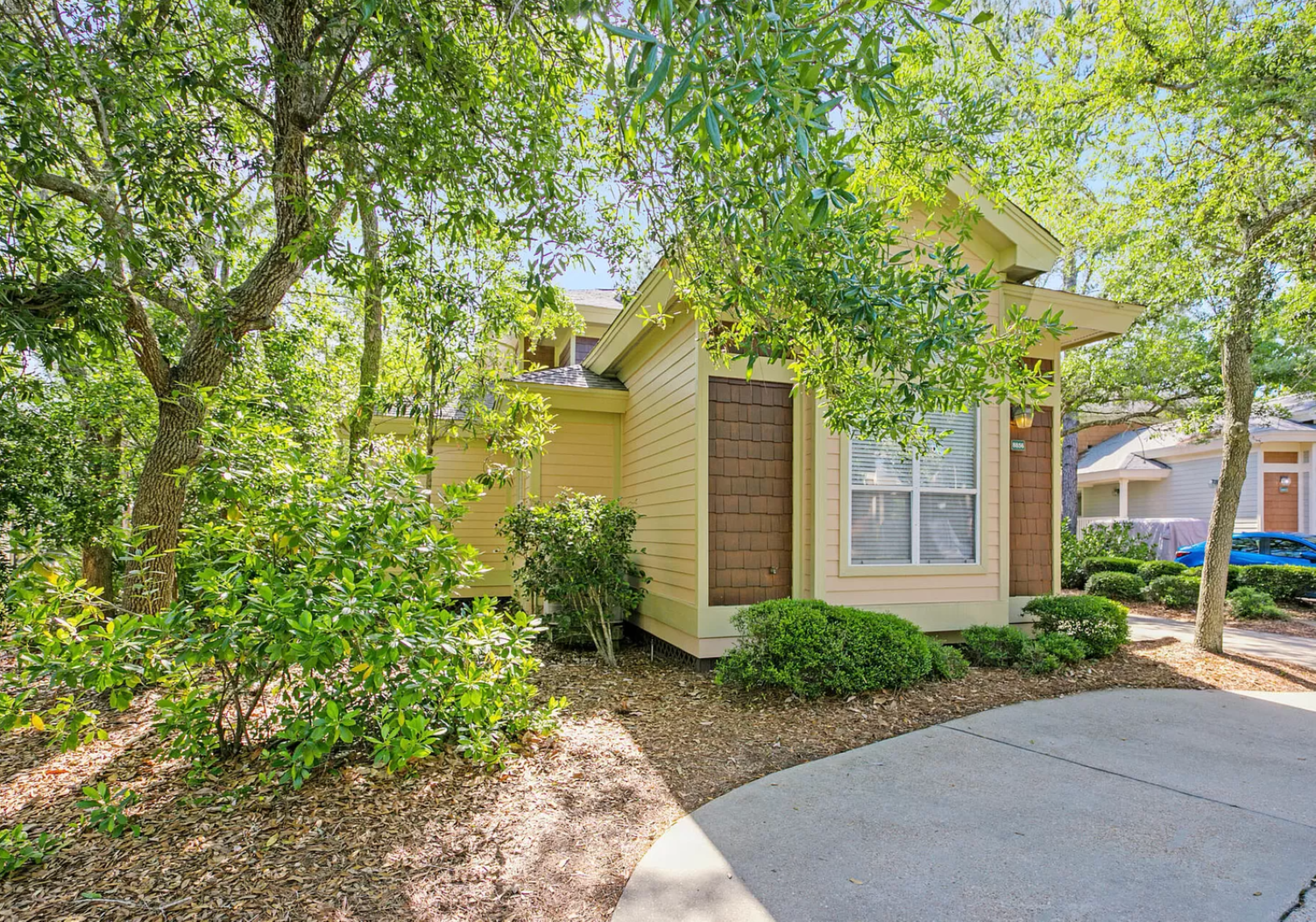 Beautiful house surrounded by mature trees and tidy landscaping.