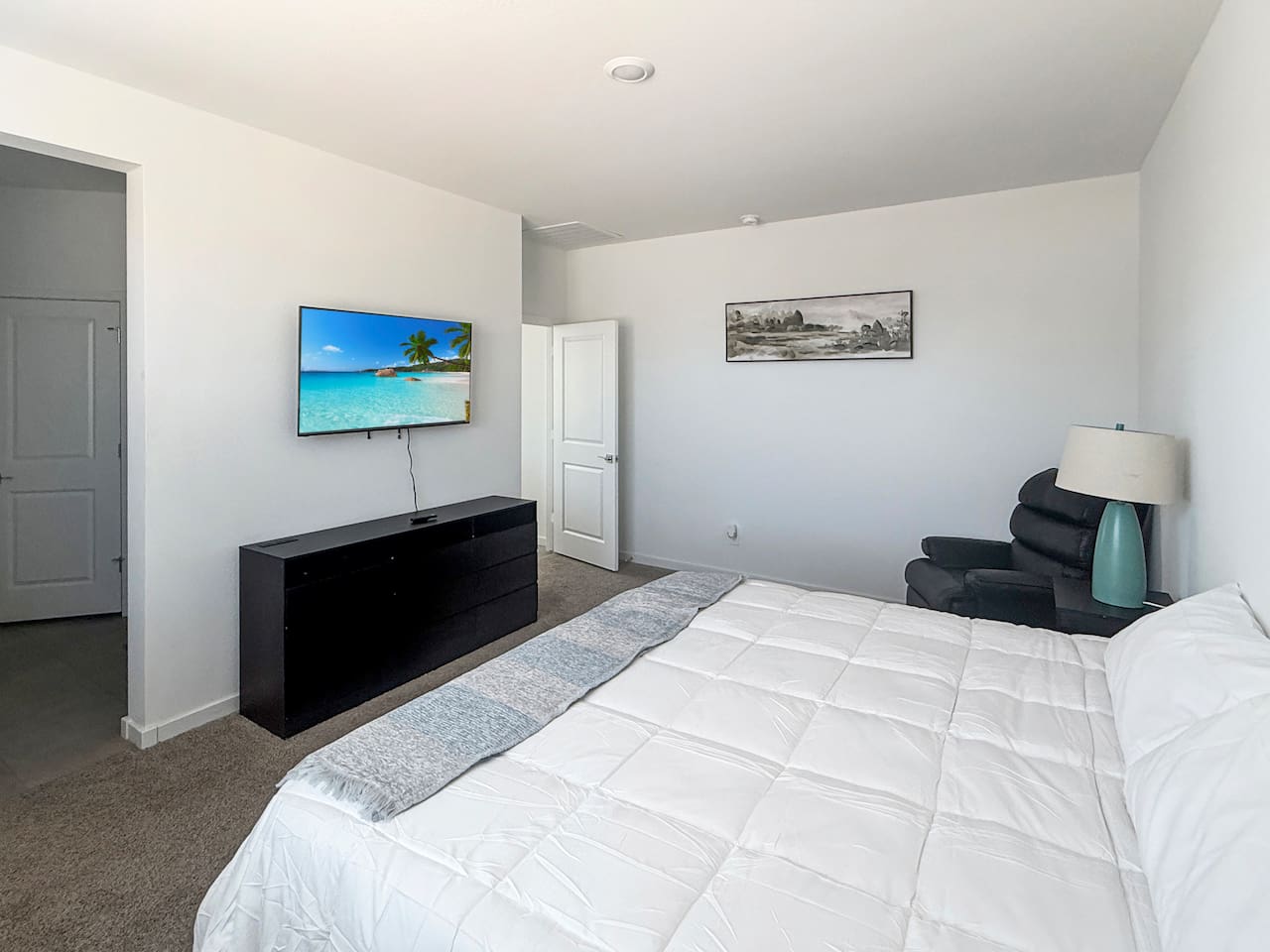 Bedroom with bed, TV, dresser, chair, and lamp