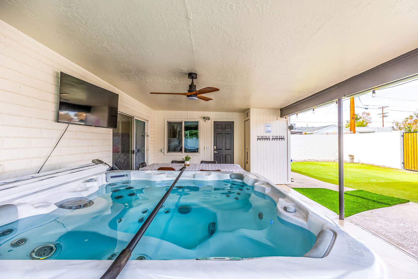 TV, shade, and soak – this patio spa setup has it all: comfy seating, privacy, and easy entertainment access.