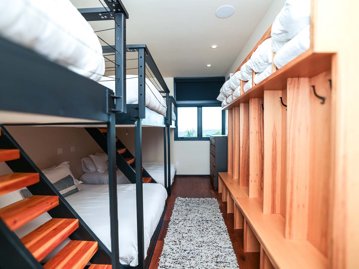 Six queen-over-queen bunk beds with cable-rail safety, cherry hardwood treads, and west-facing window in the Sunset Falls bunk room