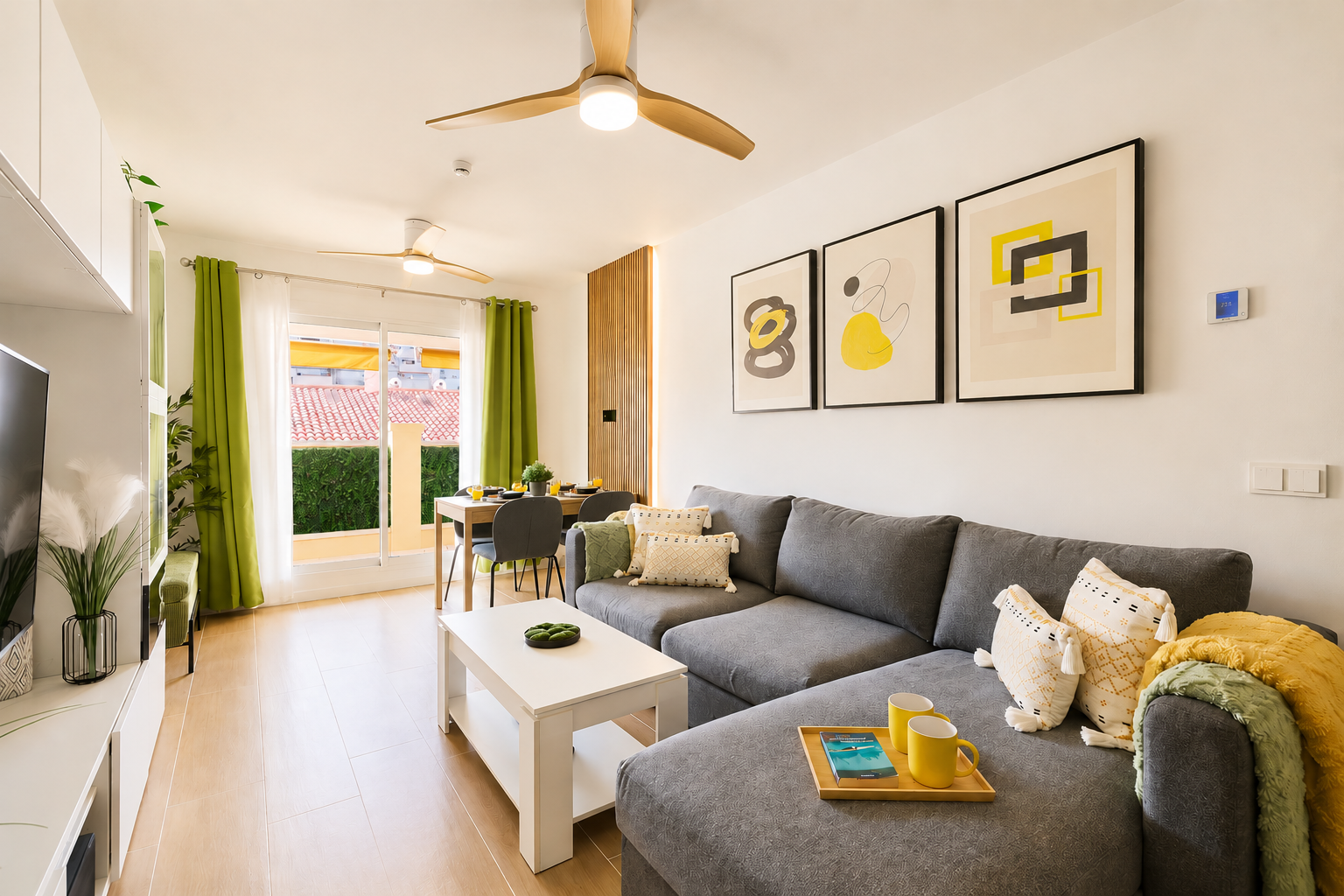 Stylish open-plan living room with a modern kitchen, smart TV, and natural light throughout — ideal for relaxing or sharing a glass of wine after a day by the beach.